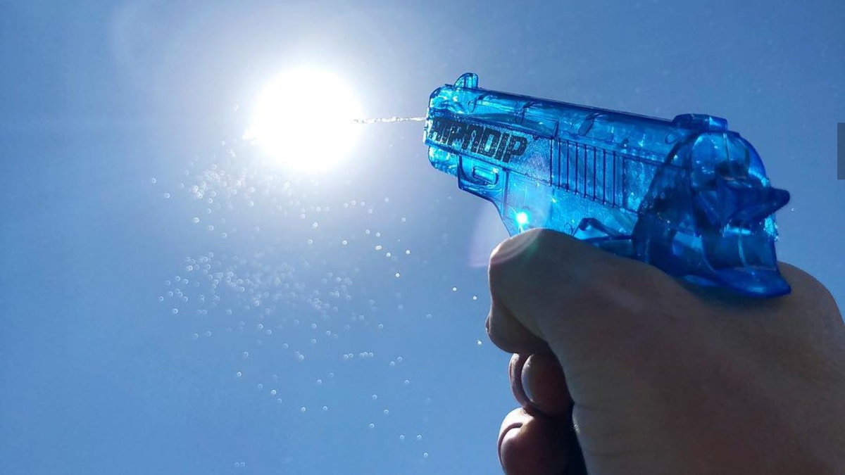 Person firing a water pistol at the sun